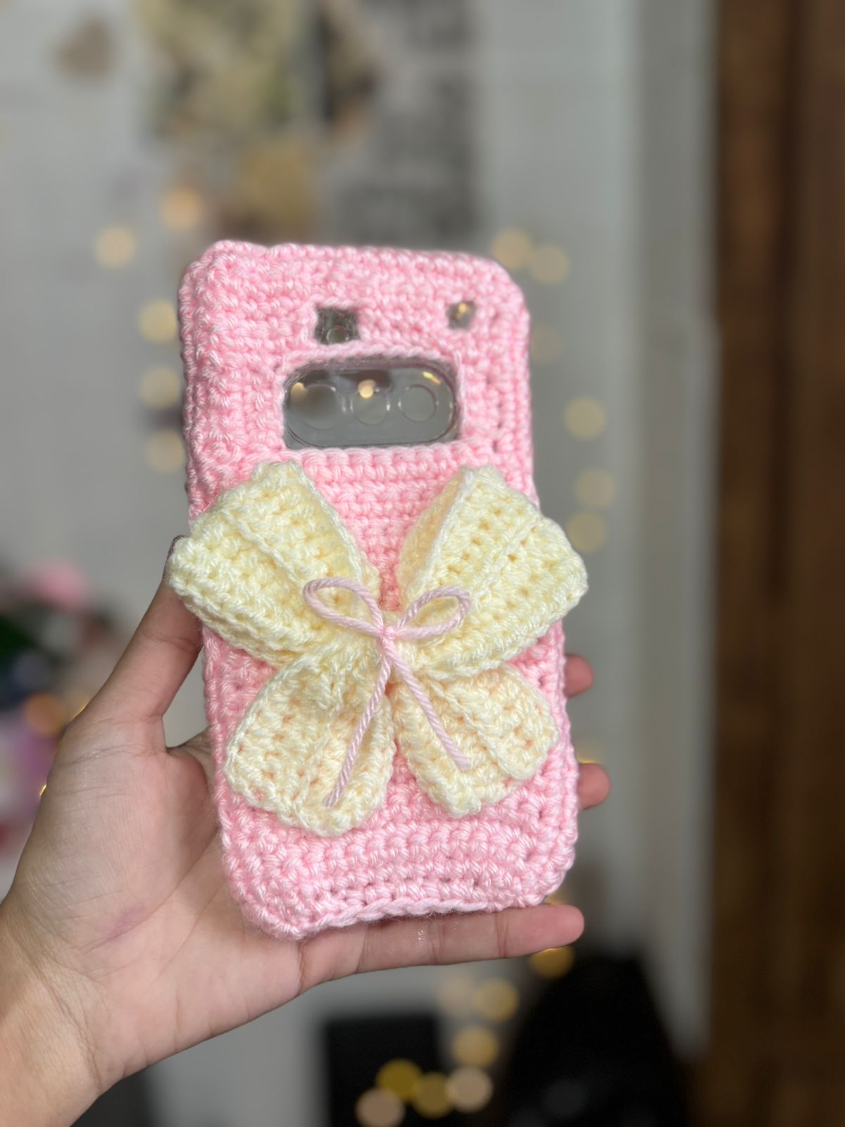 Handmade pink crochet bow phone case with soft wool texture and cute aesthetic design